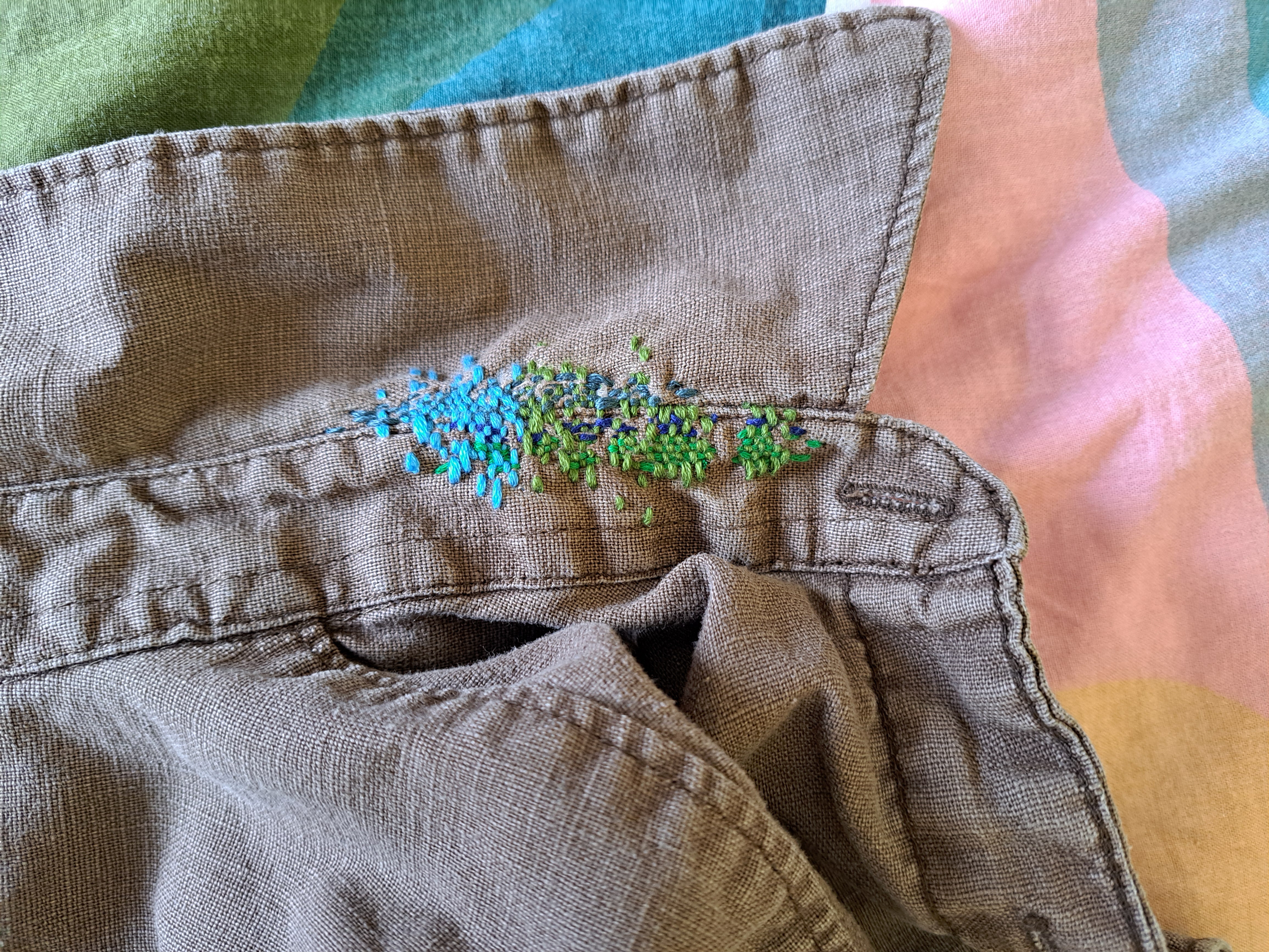 visible mending in blue and green on collar of beige shirt
